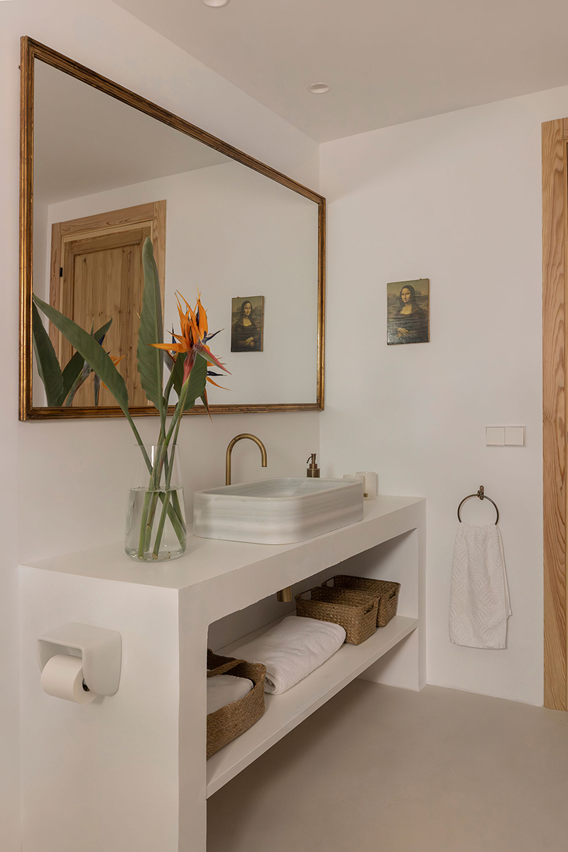 Baño con lavabo de mármol, espejo vintage y mueble de obra blanco