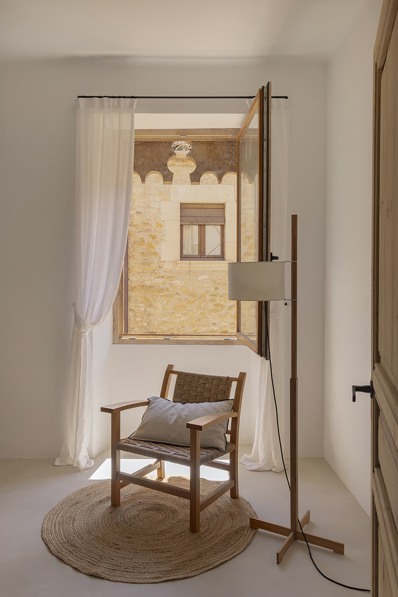Dormitorio con ventana abierta hacia la arquitectura histórica de Vulpellac