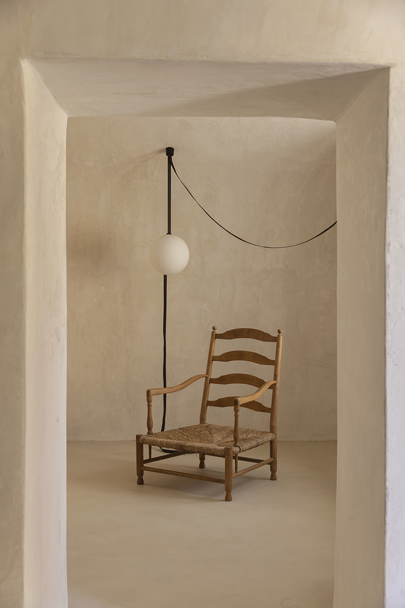 Rincón del salón con silla vintage restaurada y lámpara contemporánea