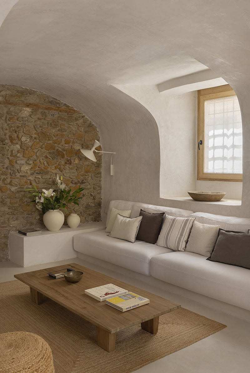 Salón con muros de piedra, estucos de cal y madera natural